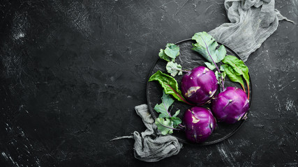 Purple kohlrabi cabbage. On a black stone background. Top view. Free space for your text.