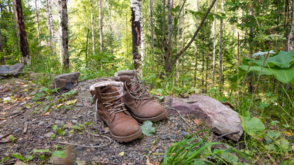 Old boots stand in the forest. Old tourist shoes