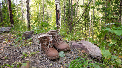Old boots stand in the forest. Old tourist shoes
