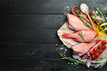 Fish raw snapper with lemon and rosemary. On a black background. Top view. Free space for your text.