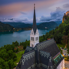 Bled, Slovenia - Aerial panoramic view of the beautiful St. Martin's Parish Church at blue hour with Bled Castle (Blejski Grad) and Julian Alps at the background with amazing clouds and sky