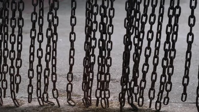 The metal chain is swinging. Heavy metal chain pendulum moves