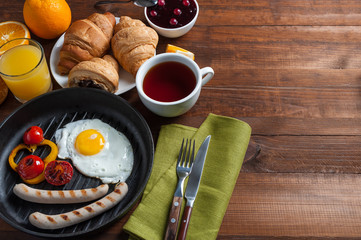 Fried eggs with sausage and vegetables on pan