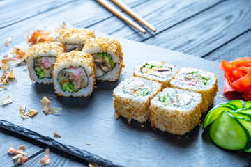 Close up sushi roll with cream cheese and crab. Sushi on stone dark plate on black wooden background with copy space. Japanese food. Seafood. Dieting, healthy