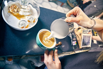 professional service at cafe concept. Barista Making of cafe latte art. pouring milk in glass of fresh made coffee. Milk and coffee toned picture. Hand of Barista making latte or cappuccino