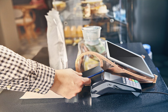 Close up view on contactless payment through the POS terminal in cafe. Cashbox concept. Paying with smartphone. paying with smartphone in shop using NFC technology. commerce. Toned picture