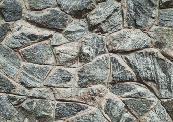 Old stone of wall texture. Lots of granite cobblestones. Close up.