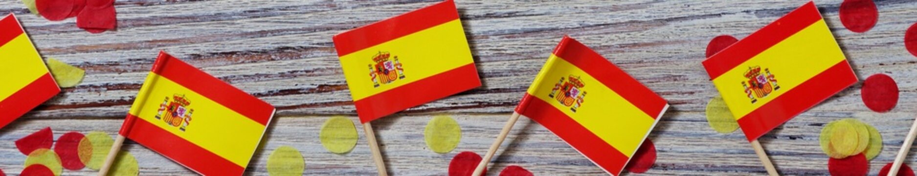 October 12. Independence day Spain concept of independence , patriotism and freedom. Mini paper flags with yellow red confetti on wooden background. banner