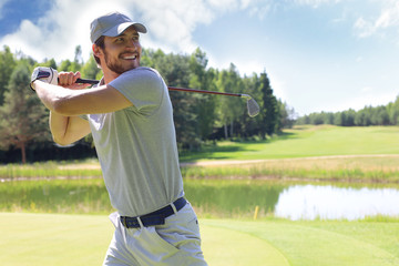 Golfer hits an fairway shot towards the club house.