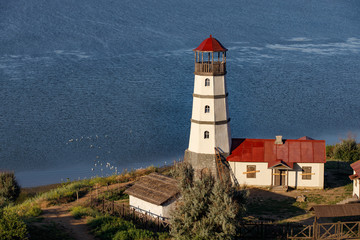 Fototapeta na wymiar Old lighthouse with a red roof on the sea shore in the morning