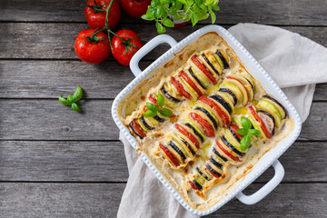 Ratatouille in baking dish on wooden rustic background. Traditional French Provencal vegetable...