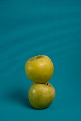 Two green apples on a light blue background.
