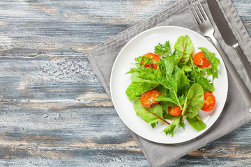 Vegetables salad in a plate on a wooden background.  Top view