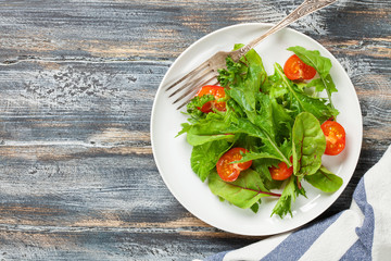 Vegetables salad in a plate on a wooden background.  Top view