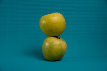 Two green apples on a light blue background.