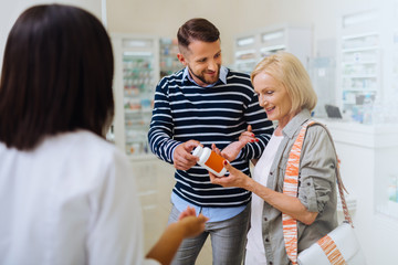 Cheerful blonde woman holding package with vitamins