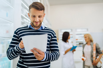 Positive delighted brunette male reading his prescription