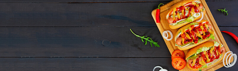 Delicious homemade hot dog on dark background. Top view. Banner.