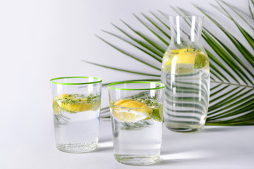 Bottle and glasses of infused water on light background