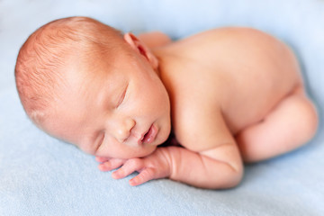 Little baby is sleeping on a blue blanket