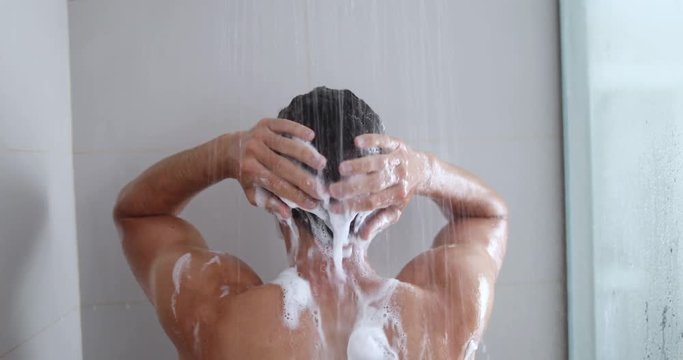 Man taking a shower washing hair with shampoo product under water falling from luxury rain shower head. Morning routine luxury hotel lifestyle guy showering. body care hygiene. 4K (UHD) 59.94 FPS SLOW