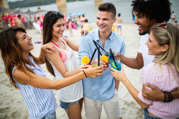 Group of friends hanging out with cocktails at the beach