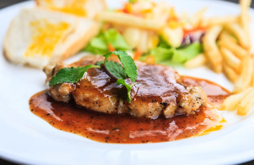  steak served with mash potato and fresh green herb salad accompanied by a BBQ sauce.