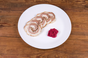 Sliced baked roll of pork belly with horseradish sauce