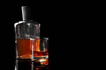 Glass and bottle of whiskey on dark background