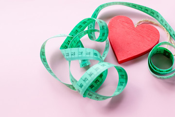 healthy heart. green measuring tape on pink background. Weight control concept. Patient health...