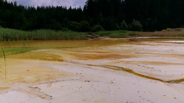 Orange dangerous water bed pan shot on abandoned kaolin quarry , polluting the water.