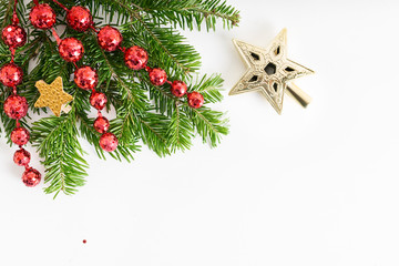 Top view flat lay natural Christmas tree branches with red toys, bow and glass reindeer corner frame on bright background. New year decor concept. Text space