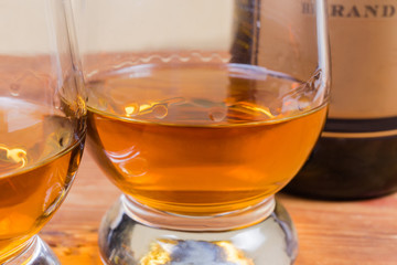 Brandy in glass against of bottle, fragment close-up
