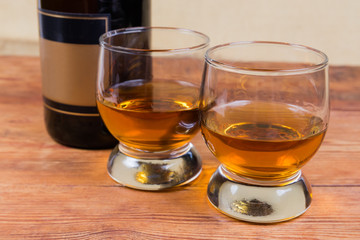 Brandy in two glasses against of bottle in selective focus