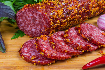 Partly sliced salami covered with French mustard close-up