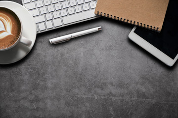 Office equipment, laptops, tablets, pens, smartphones, notebooks and coffee cups on a Cement wall table background Top view from the top.