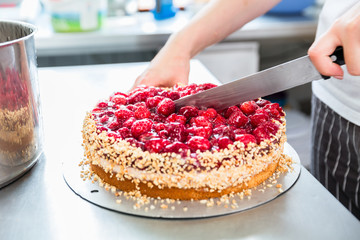 Close-up of woman confectioner cutting raspberry pie