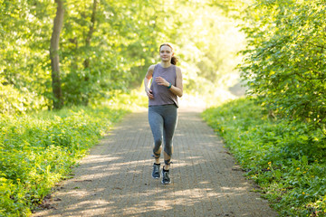young woman running in a forest and makes fitness