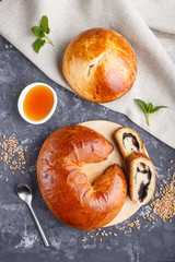 Homemade yeast buns and rolls with poppy seeds and honey on a black concrete background. top view.