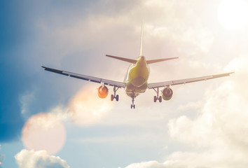 Airplane flying in sky with clouds on sunny day.