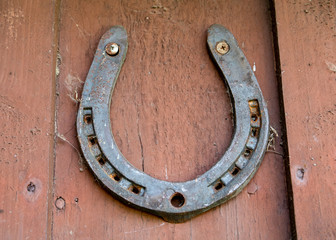 Old rusty horseshoe on wooden wall background. Symbol of luck concept
