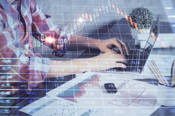 Double exposure of stock graph with businessman typing on computer in office on background. Concept of hard work.