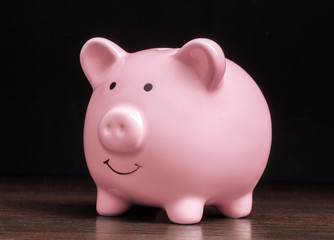 pink piggy bank on wooden table on black backdrpop