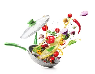 Foto auf Acrylglas Essen Kochkonzept. Gemüse fliegt aus der Pfanne auf weißem Hintergrund. Gesundes Essen.