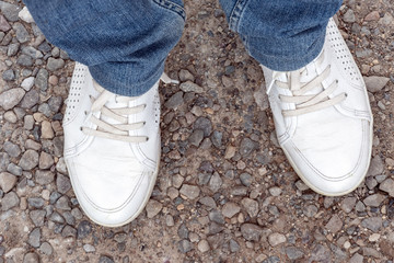 Legs of a person in jeans and white sneakers. Go off road.