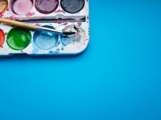 multicolored paint and brush on blue background
