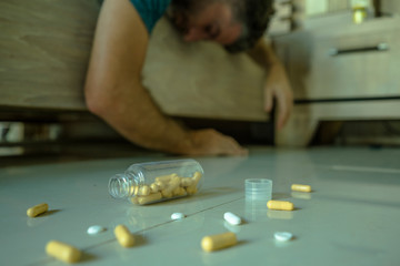 passed out  man suffering depression lying unconscious on bed at home after having pills overdose intoxicated by mix of antidepressant medicines in suicide attempt