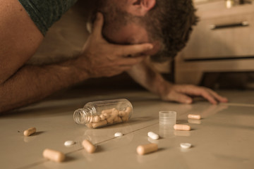 intoxicated man suffering depression crying on bed floor at home after having pills overdose intoxicated by mix of antidepressant medicines regret on suicide attempt