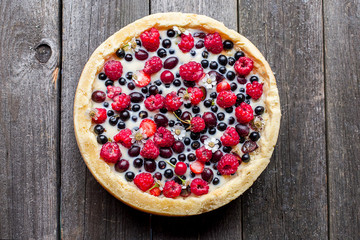 tart with different berries on a old wooden background