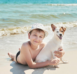 Child boy with dog jack russel on beach. Best friends rest on vacation, play in sand against sea. Tourism and vacation on ocean. Family vacation in summer. Vacation at sea with dog. Summer travel